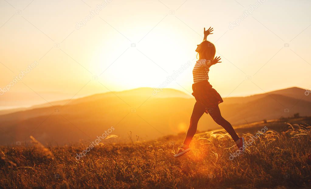 Happy woman jumping and enjoying life  at sunset in mountain