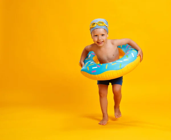 Glücklicher Junge im Badeanzug mit Schwimmring-Donut auf farbigem — Stockfoto