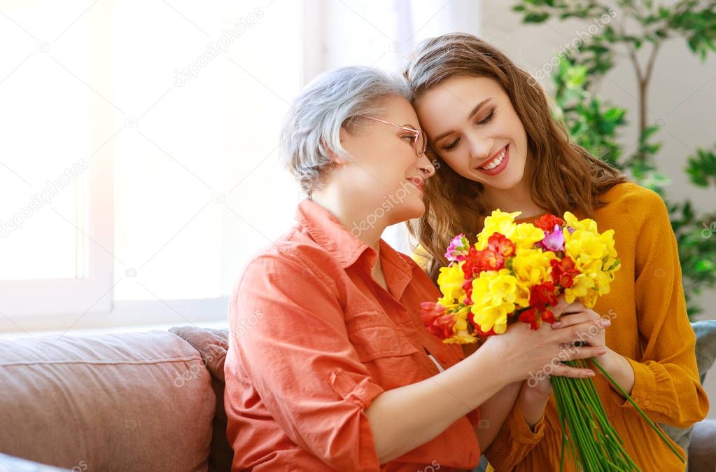 Happy mother's day! adult daughter gives flowers and congratulat