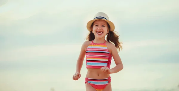 Happy child girl  with swimsuit and hat  on  beach at sunse — Stock Photo, Image