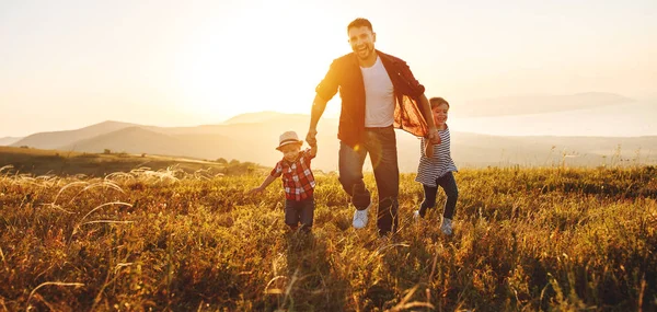 Счастливый отец семьи и дети на природе на закате — стоковое фото