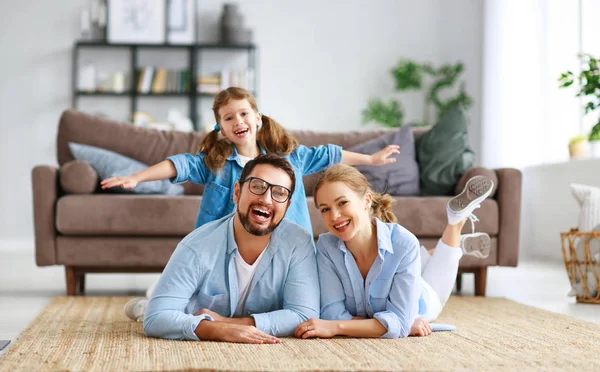 Família feliz mãe pai e filha criança em casa no sofá — Fotografia de Stock