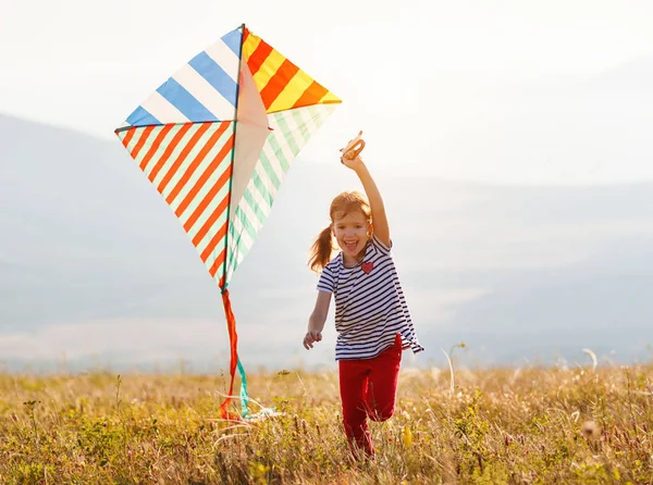 Happy child girl running with kite at sunset outdoor — Stock Photo, Image