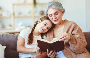 happy family grandmother reading to granddaughter book at home   clipart