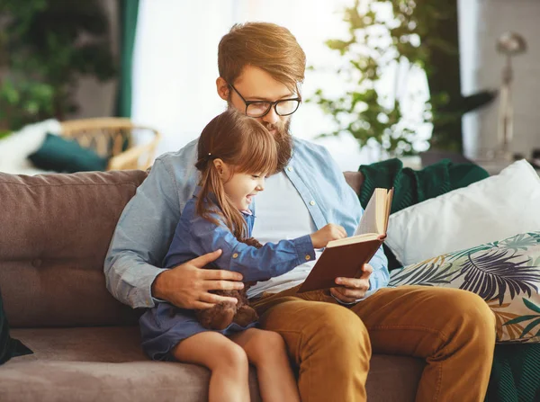 Família feliz. pai lendo um livro para uma filha criança em casa — Fotografia de Stock