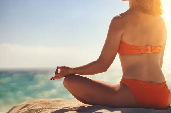 Женщина практикует йогу и медитирует в позе лотоса на пляже — стоковое фото
