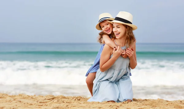 Glückliche Familie am Strand. Mutter und Tochter umarmen sich auf See — Stockfoto