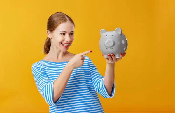 幸福的女人与小猪钱银行在粉红色的背景。金融 — 图库照片