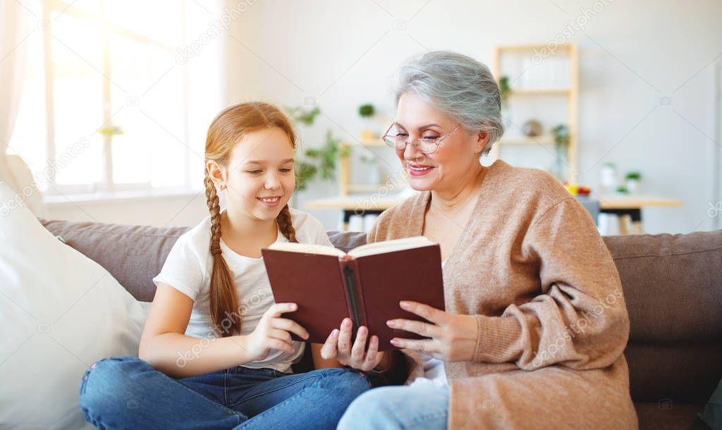 happy family grandmother reading to granddaughter book at home  