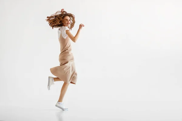 Щаслива молода жінка стрибає на білому тлі — стокове фото