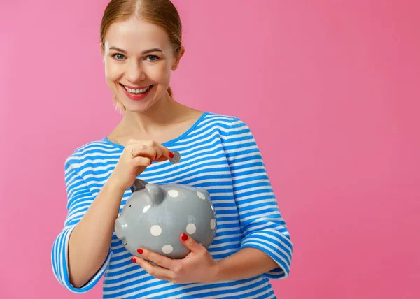 Mujer feliz con alcancía en el fondo rosa. financiera —  Fotos de Stock