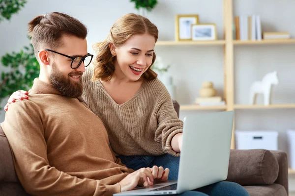 Feliz pareja con ordenador portátil en casa —  Fotos de Stock