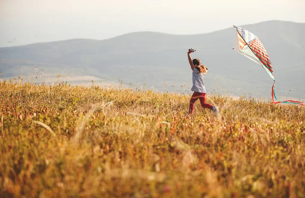 愉快的孩子女孩跑与风筝在日落户外 — 图库照片