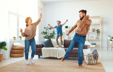 Mutlu aile, anne, baba ve kız evde dans ediyor.  