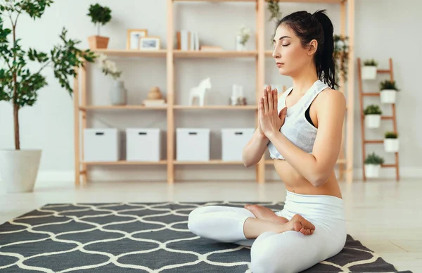 Frau macht Yoga, meditiert zu Hause in Lotusposition — Stockfoto