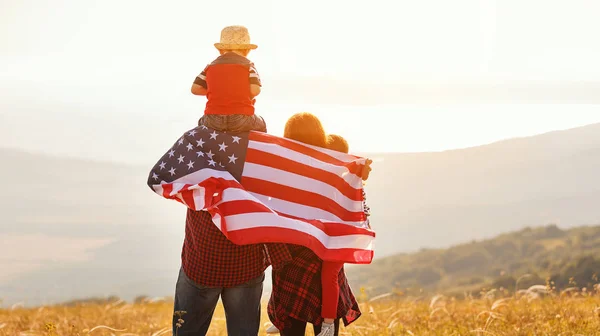 Счастливая семья с флагом США на закате под открытым небом — стоковое фото