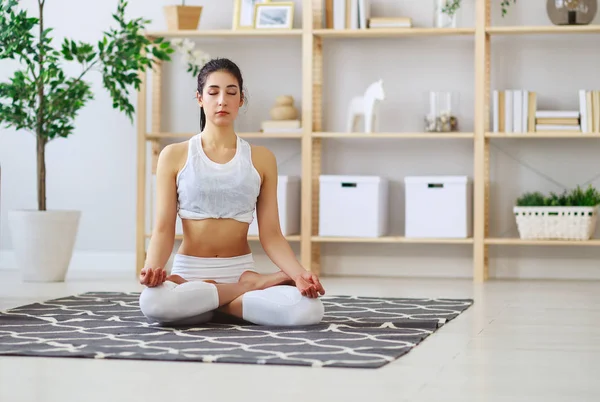 Mujer haciendo yoga, meditando en posición de Loto en casa —  Fotos de Stock