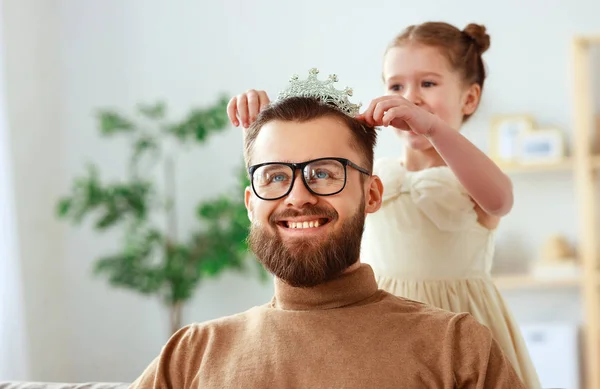 ¡Feliz día del padre! niño hija en corona hace maquillaje a papá —  Fotos de Stock