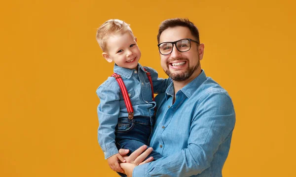 Lycklig fars dag! Söt pappa och son kramas på gula bakgrunds — Stockfoto