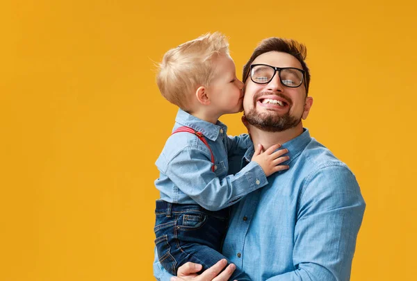 Šťastný den otců! roztomilý táta a syn, co se pletou do žlutého pozadí — Stock fotografie