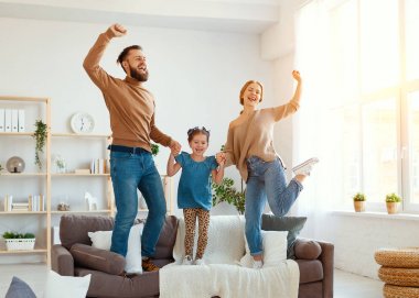 Mutlu aile, anne, baba ve kız evde dans ediyor. 