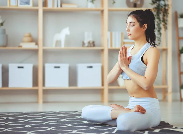 Mujer haciendo yoga, meditando en posición de Loto en casa —  Fotos de Stock