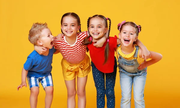 Grupo de crianças felizes alegres em backgroun amarelo colorido — Fotografia de Stock