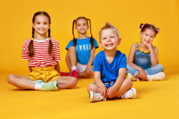 Grupo de alegres niños felices en el fondo amarillo de color — Foto de Stock