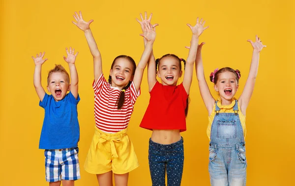 Grupo de crianças felizes alegres em backgroun amarelo colorido — Fotografia de Stock