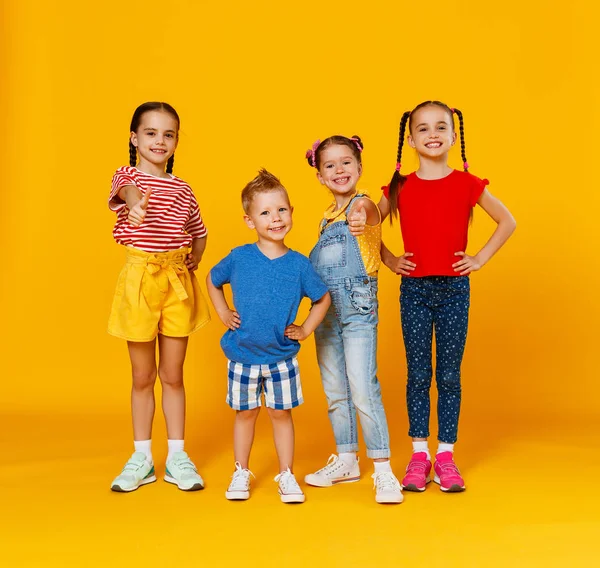 Grupo de alegres niños felices en el fondo amarillo de color — Foto de Stock