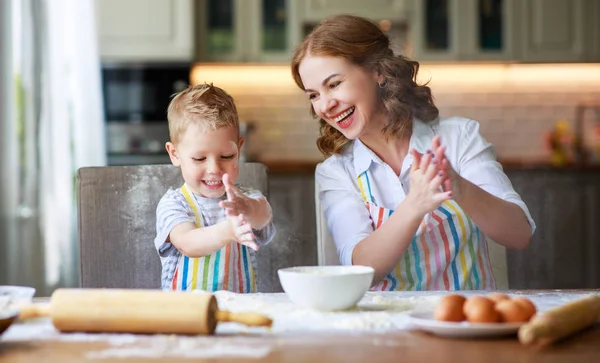 Happy family mother and son bake kneading dough in kitchen — Stock Photo, Image