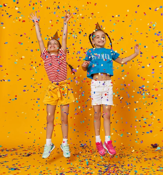 Happy children girls twins on holidays  jumping in multicolored — Stock Photo, Image