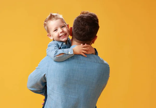 Szczęśliwy dzień ojca! cute tata i syn przytulanie na żółtym oświetlenie tła — Zdjęcie stockowe