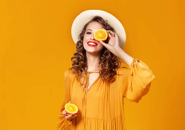 Cheerful young curly woman girl with   orange   on  yellow   bac — Stock Photo, Image