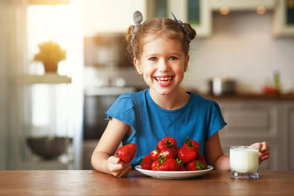 Niña feliz comiendo fresas con leche —  Fotos de Stock