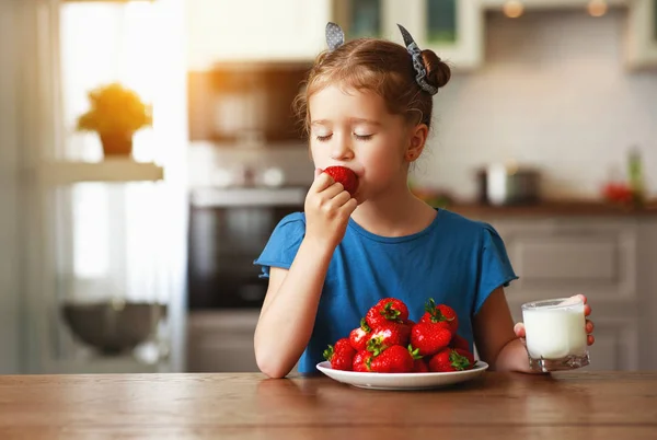 Glückliches Kindermädchen isst Erdbeeren mit Milch — Stockfoto