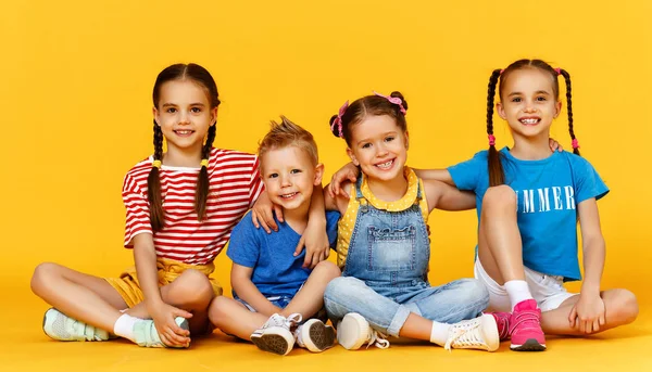 Grupo de alegres niños felices en el fondo amarillo de color — Foto de Stock