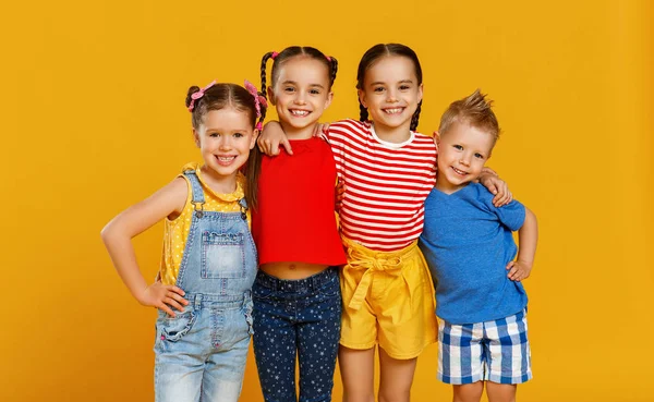 Grupo de crianças felizes alegres em backgroun amarelo colorido — Fotografia de Stock