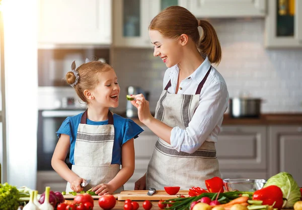 Mãe de família feliz com criança menina preparando salada vegetal — Fotografia de Stock