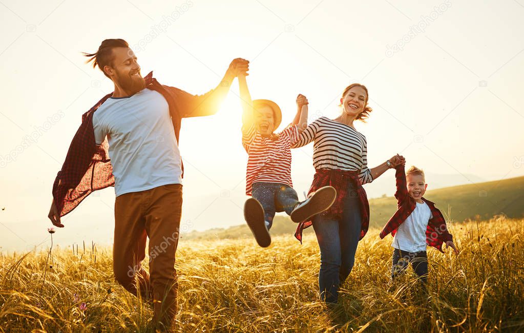 Happy family: mother, father, children son and daughter on sunse