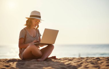 Beach niteliğine laptop ile çalışan genç kadın