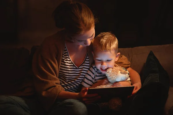 Gelukkige familie moeder en kind zoon met Tablet in de avond — Stockfoto