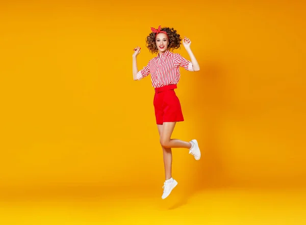 . concepto feliz emocional joven mujer en rojo saltar en yello —  Fotos de Stock