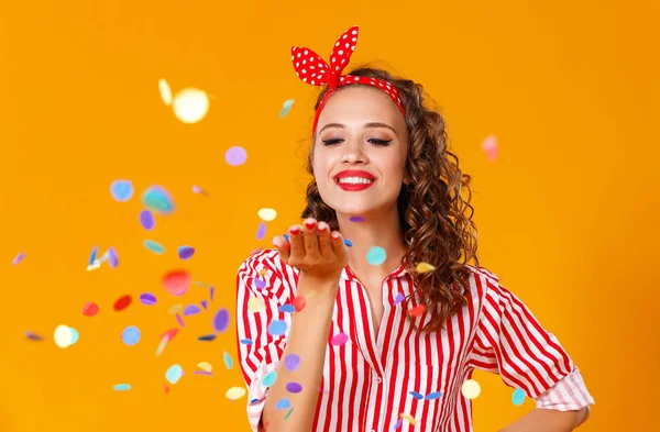 Glad rolig ung kvinna med festlig konfetti på gult — Stockfoto