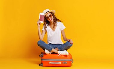 Seyahat konsepti. Bavulu ve pasaportu olan mutlu bir kadın. 
