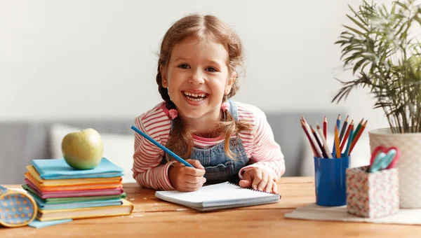 Смішна дівчинка робить домашнє завдання письма і читання вдома — стокове фото