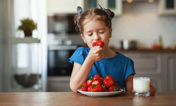 Щаслива дитина дівчина їсть полуницю з молоком — стокове фото