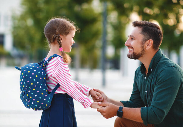 first day at school. father leads  little child school girl in f