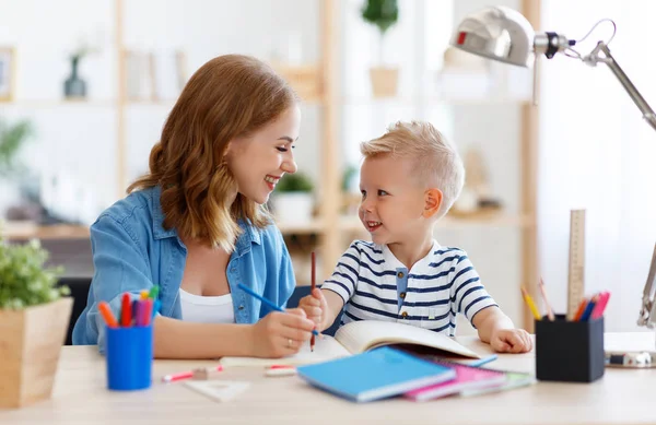 Madre e figlio figlio a fare i compiti di scrittura e lettura a casa — Foto Stock