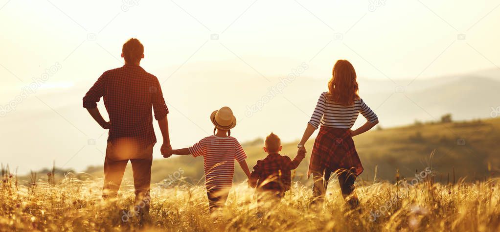 Happy family: mother, father, children son and  daughter on nature  on sunse